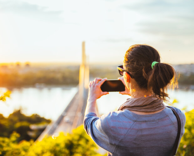 Donna che scatta foto della distanza della città di Novi Sad con uno smartphone