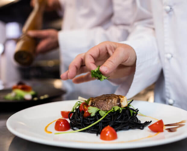 Chef guarnición de comida en el mostrador de la cocina comercial